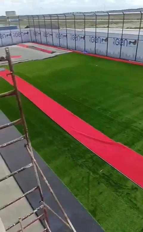 Yuxarıdan görünüş — süni qazon döşənmiş mini stadion və qırmızı kənar zolaq